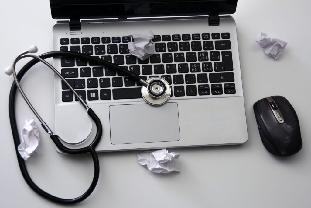 Photo of a laptop with a stethoscope laying on its keyboard.